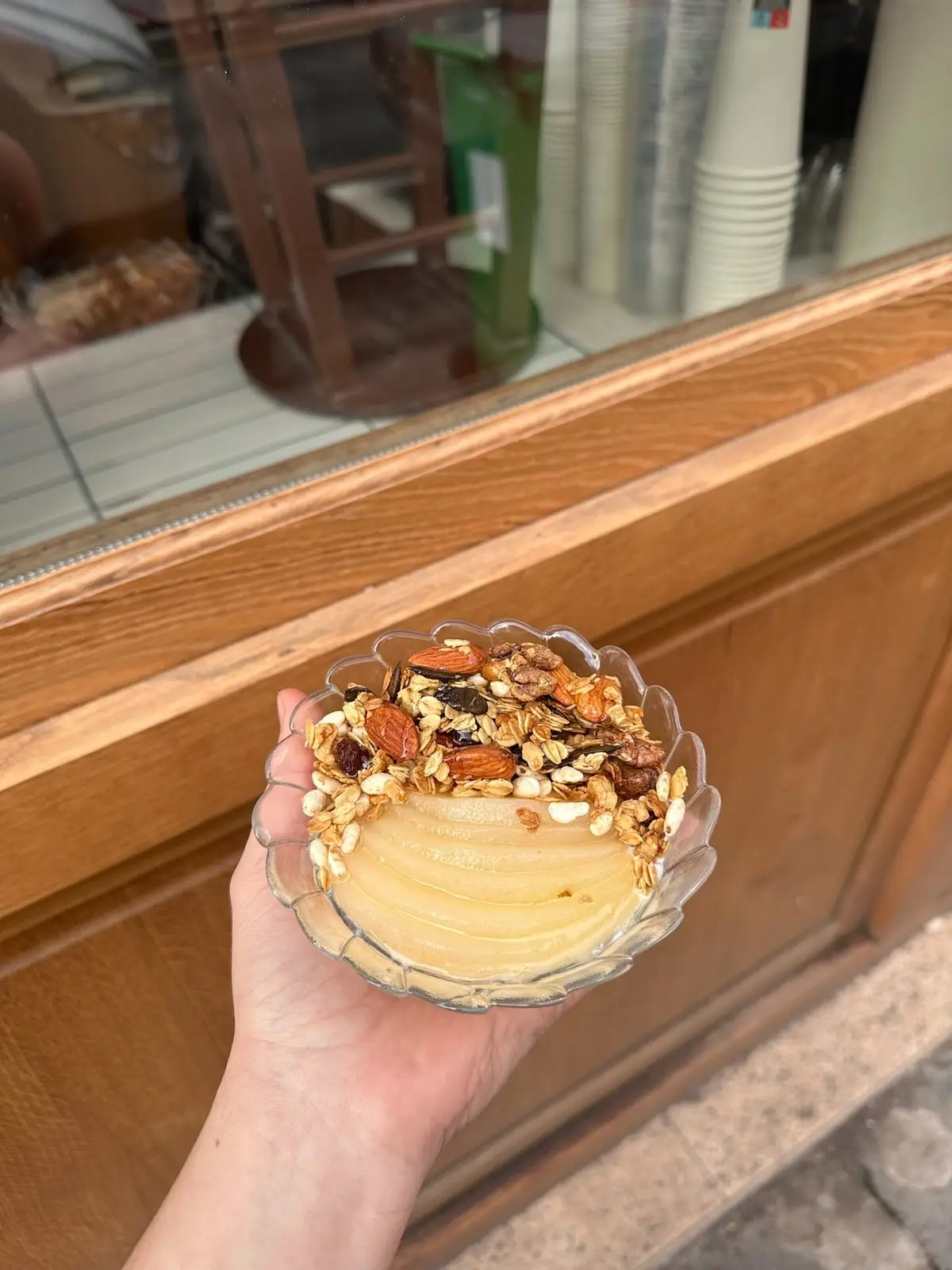 Un bol de granola aux amandes avec une poire pochée, devant la vitrine