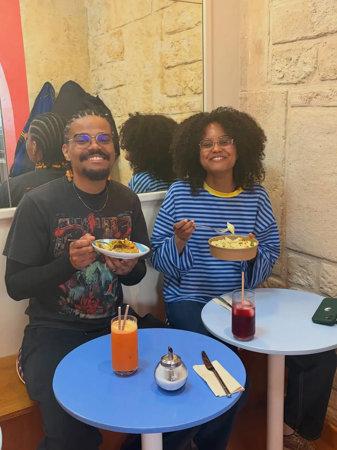 Deux client·es attablé·es avec des bols de salade et des jus frais chez Binie