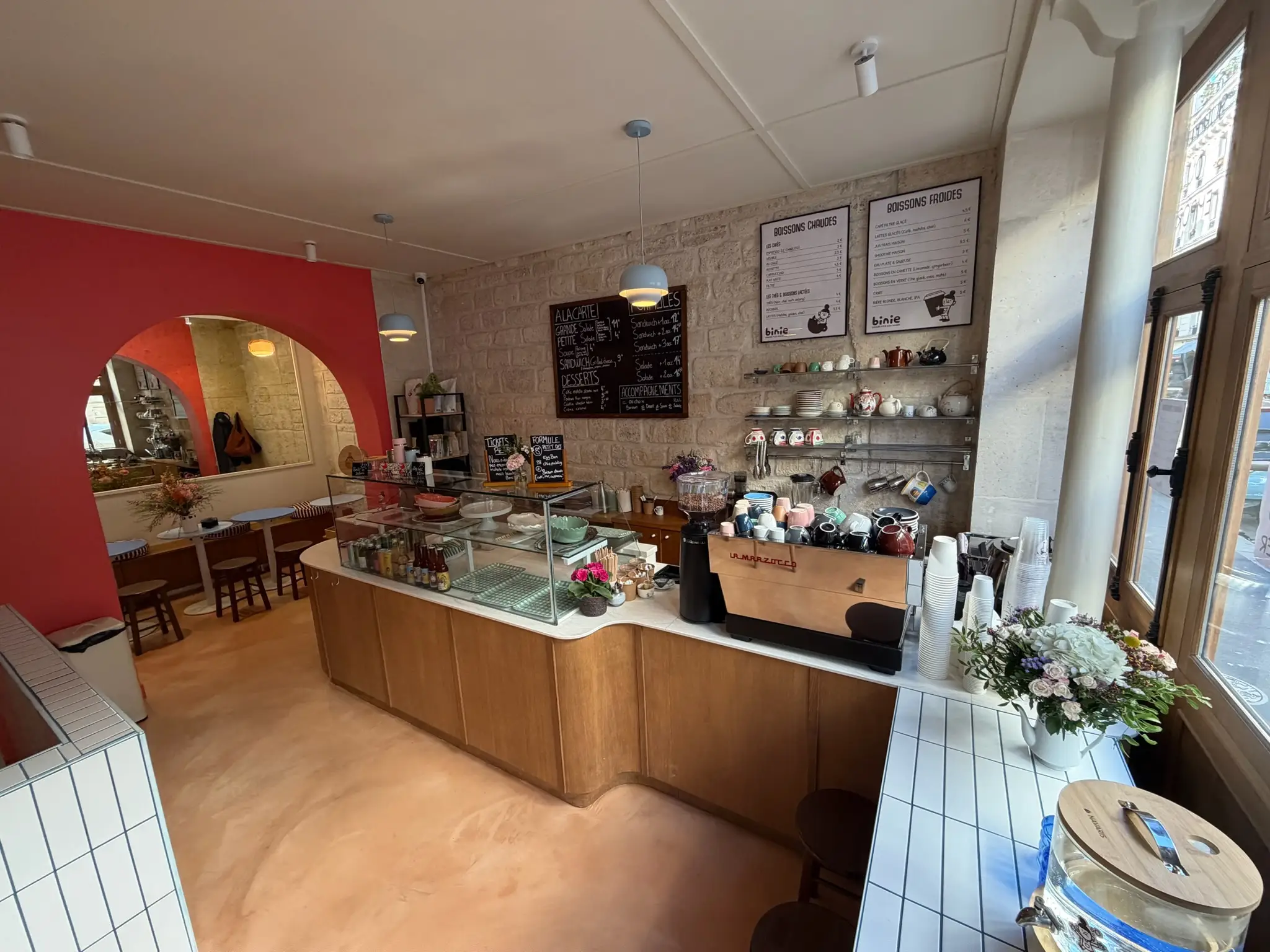 La salle de Binie : comptoir en bois, vitrine à pâtisseries et ardoises du jour
