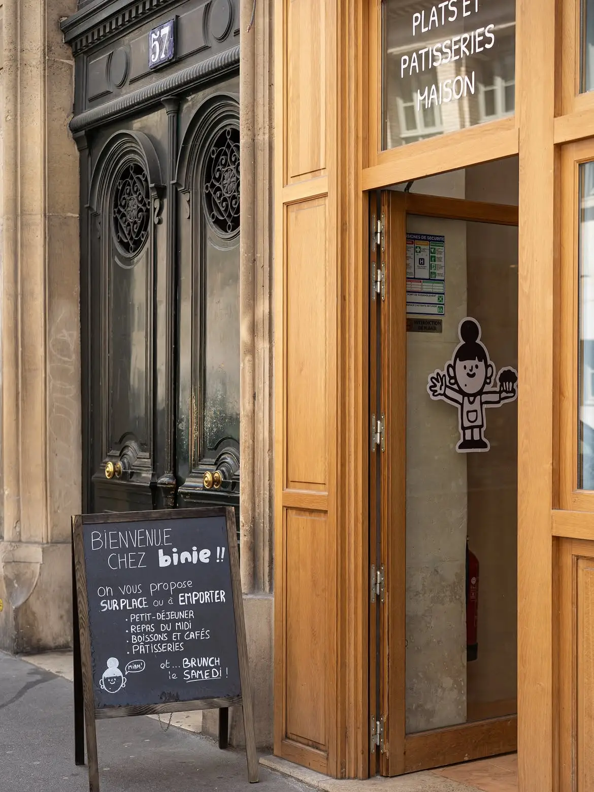 Le sticker de la mascotte Binie collé sur la vitrine, à côté de l’ardoise du jour